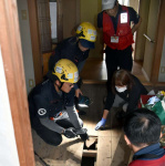 床下に流れ込んだ土砂の状況を説明するピースボート災害支援センターのスタッフ（左）＝姶良市平松