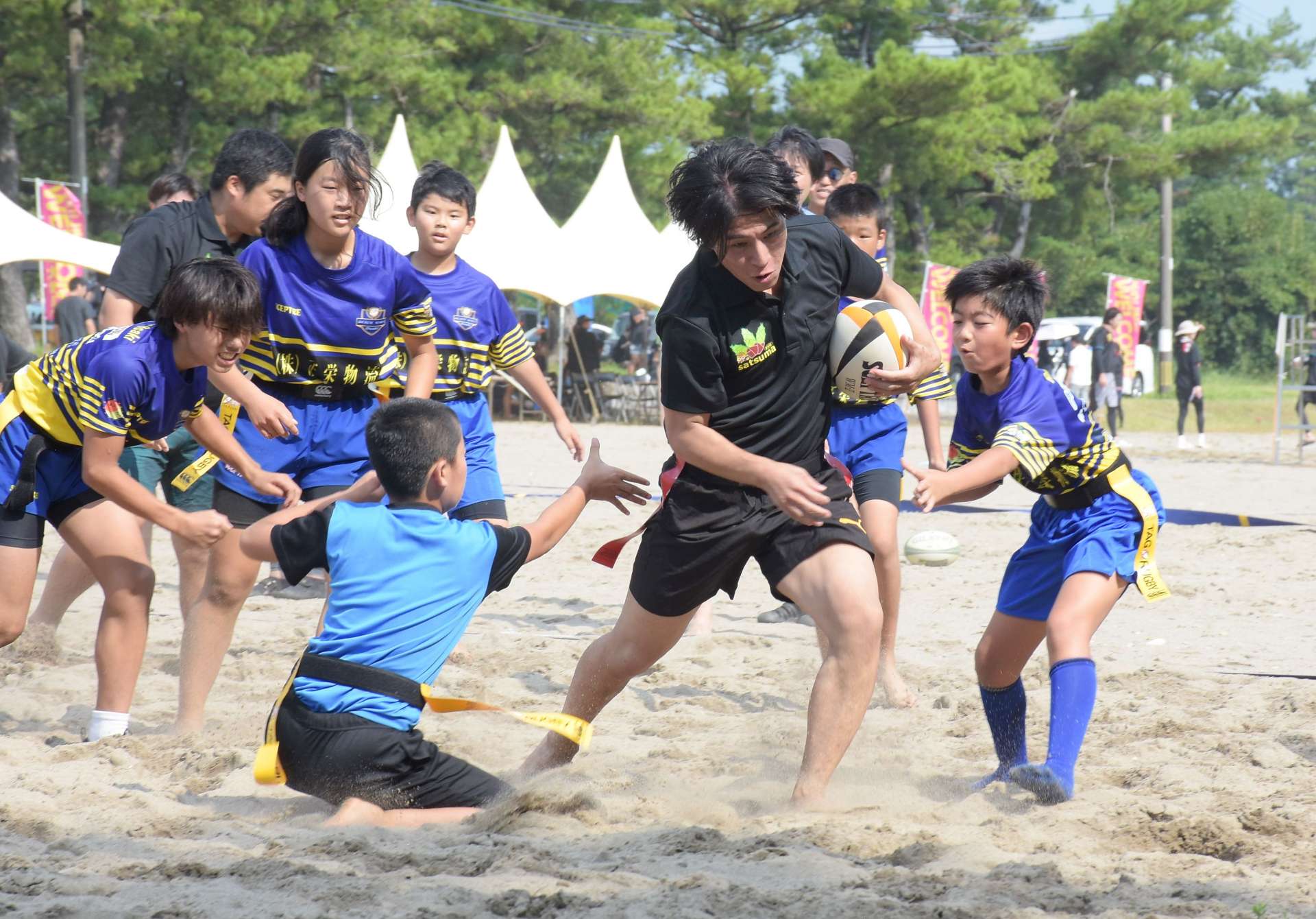 熱戦を繰り広げるビーチタグラグビー参加者＝大崎町ビーチスポーツ専用競技場