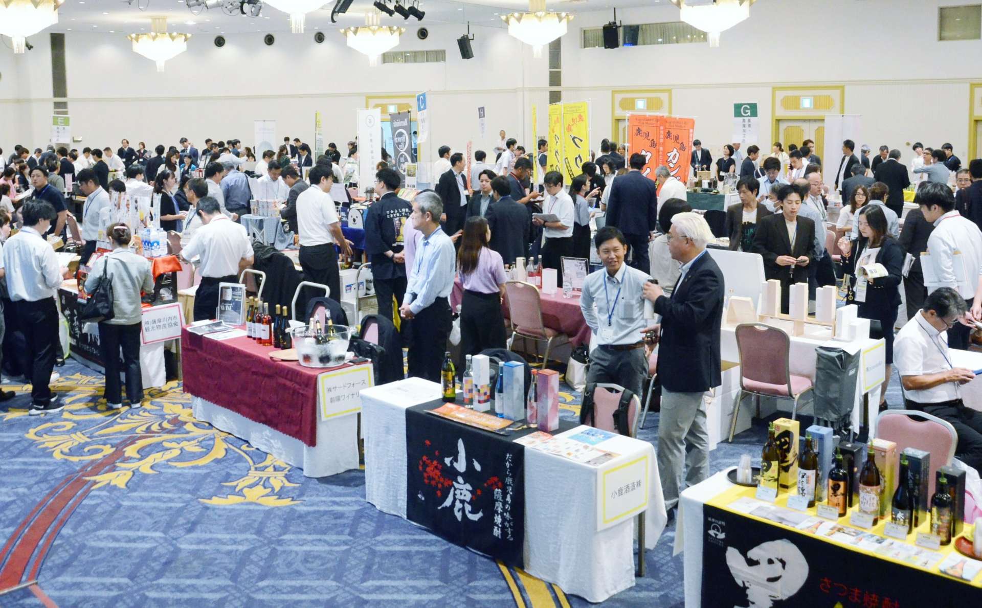 県産品の輸出拡大に向け、ブースで商談するバイヤーと出展者＝１４日、鹿児島市