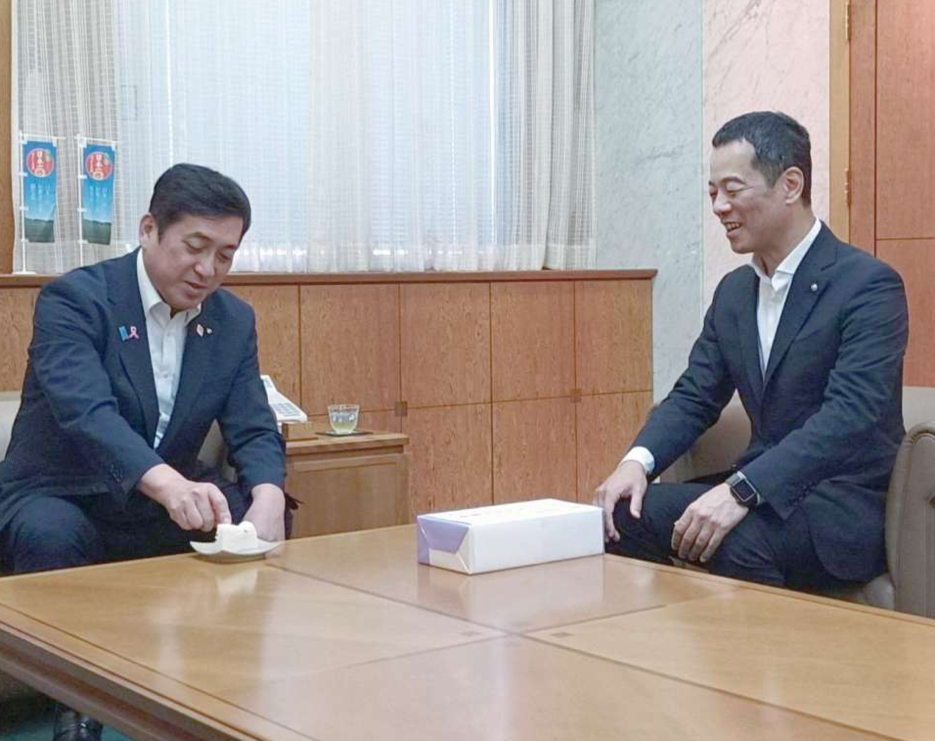 塩田康一知事（左）に新薯かるかんを勧める岩田英明理事長＝１７日、鹿児島県庁