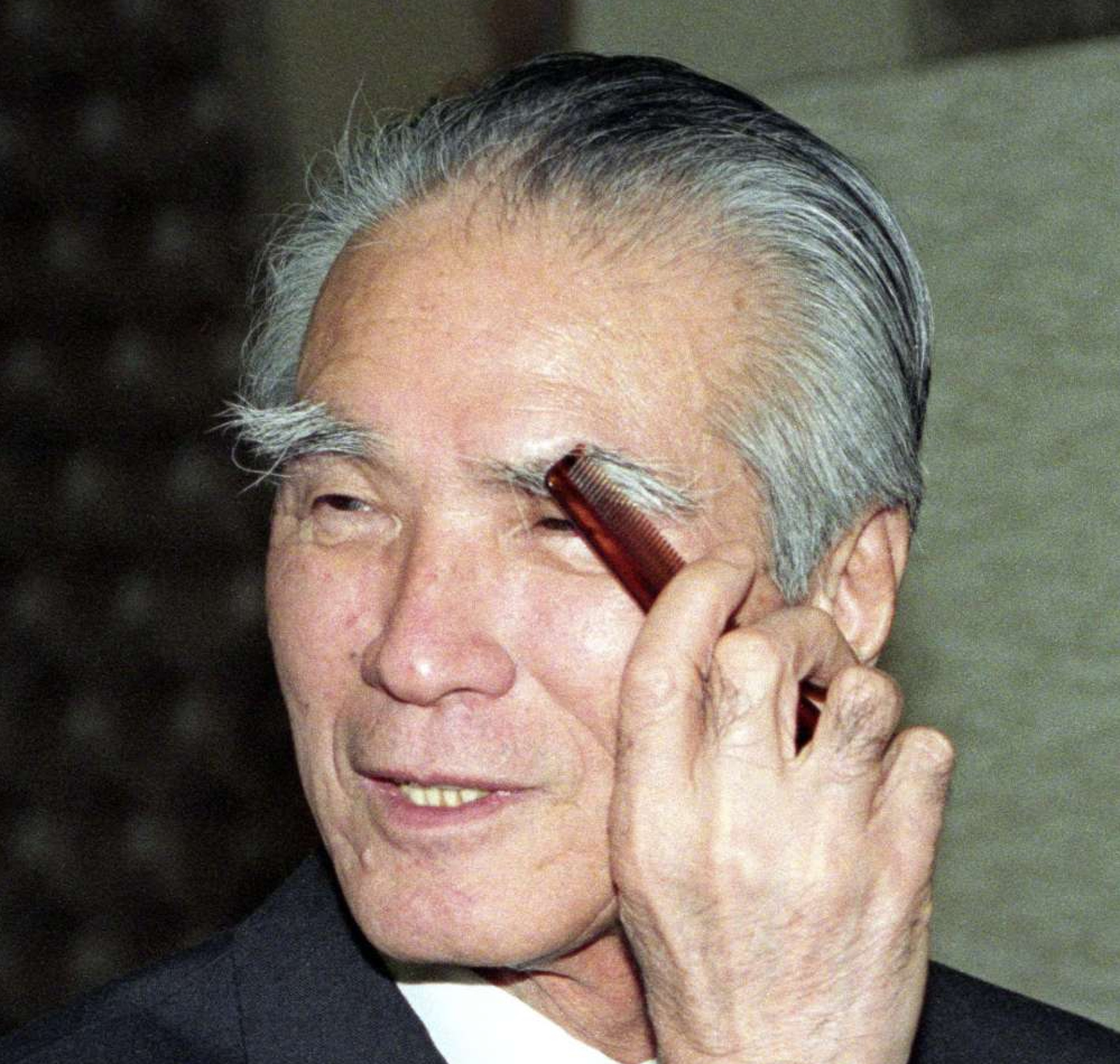 １９９５年１２月、八の字に垂れ下がったトレードマークの長い眉を整える村山富市首相＝首相官邸（共同）