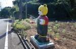 警察官人形の近くに設置されたクマの人形とコスモス畑＝南さつま市笠沙町赤生木