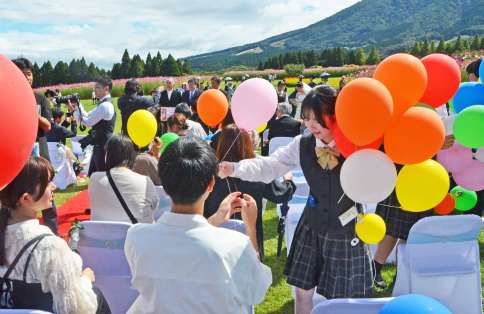 参列客にバルーンを配る小林秀峰高生＝小林市南西方の生駒高原