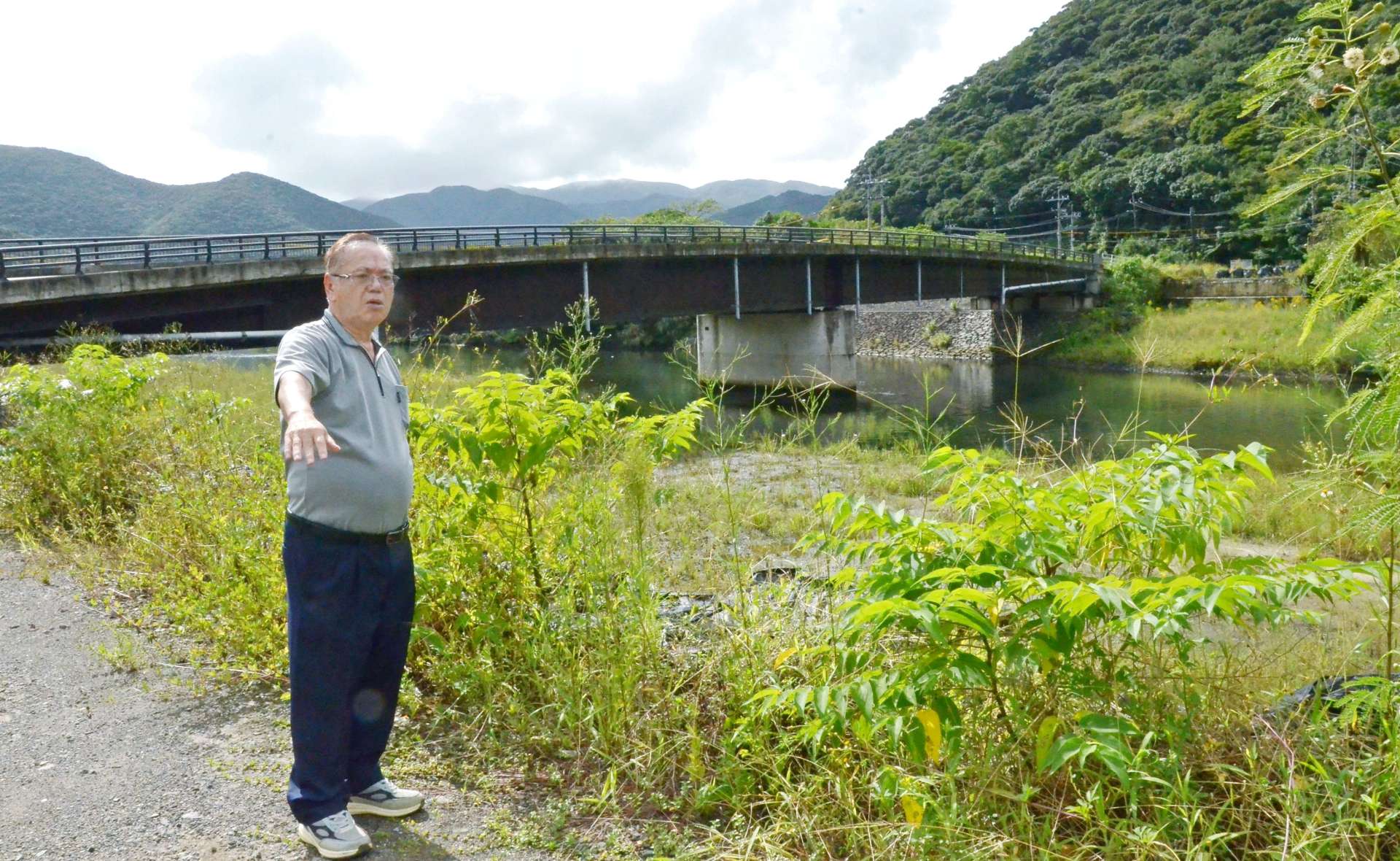 奄美豪雨で氾濫した住用川沿いに立つ満田英和さん＝２０日、奄美市住用町西仲間