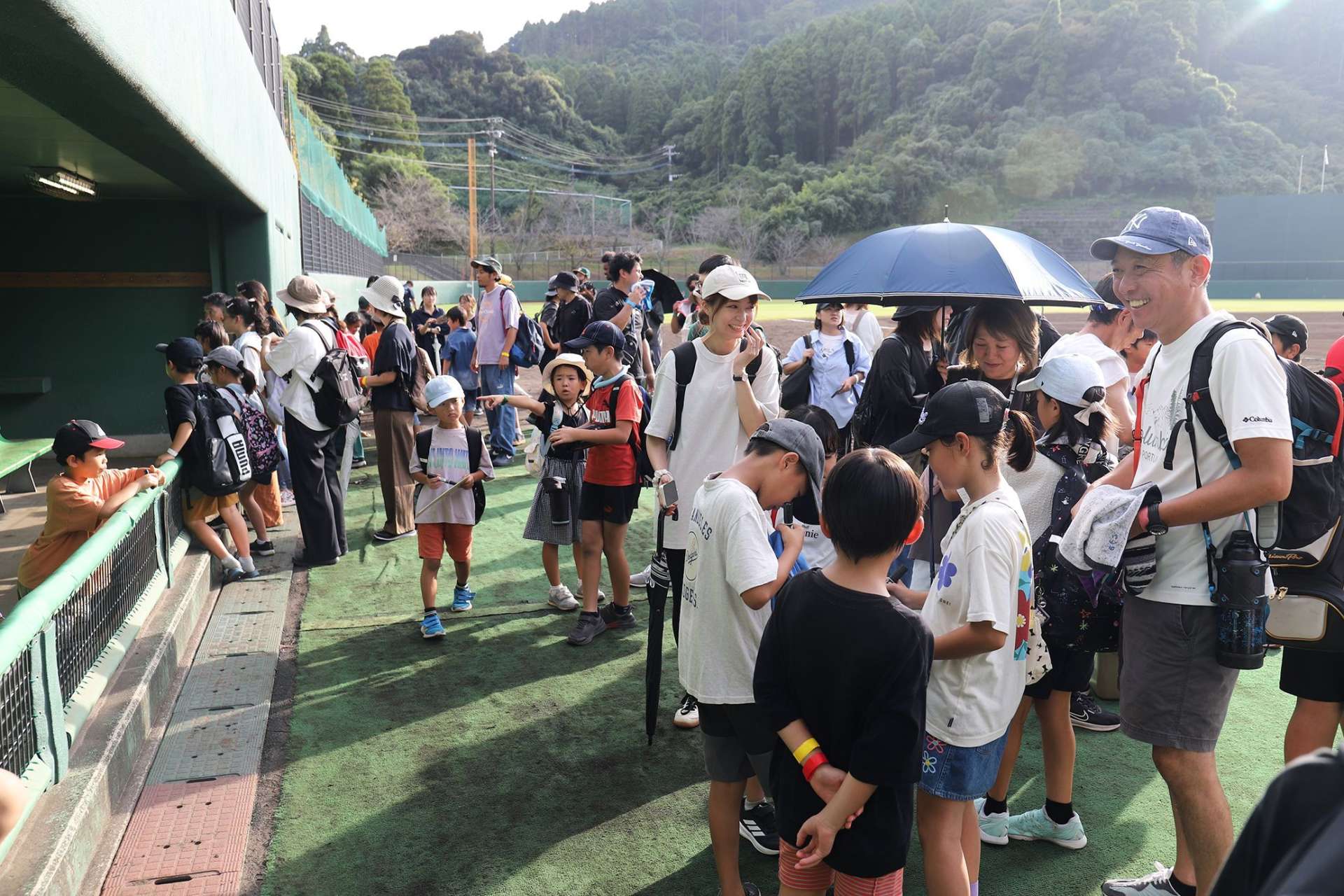 ＪＲ日南線野球観戦ツアーの試合終了後、ベンチを見学する参加者＝日南市の天福球場