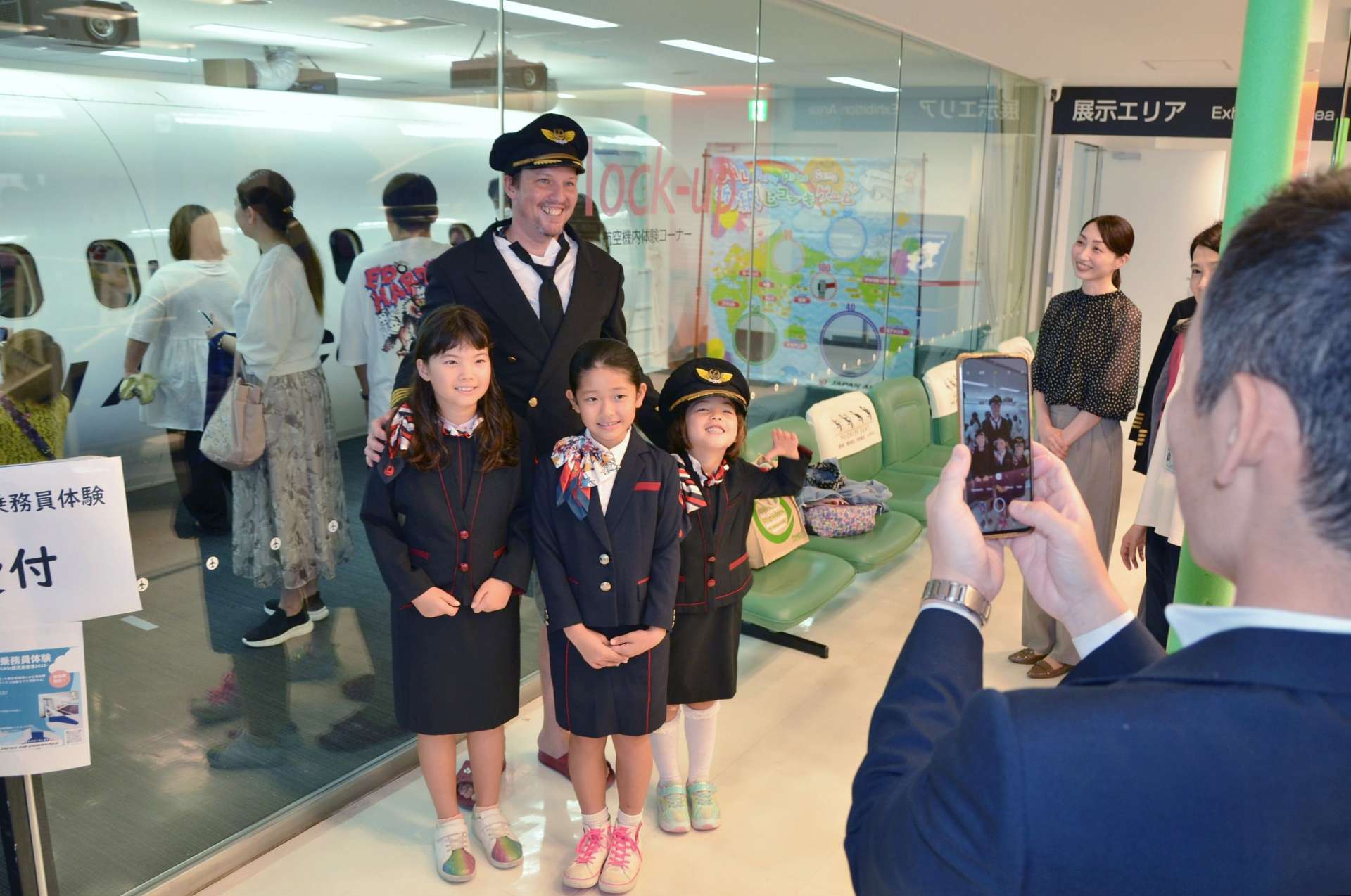 客室乗務員やパイロットの制服を試着し記念撮影する家族連れ＝霧島市の鹿児島空港