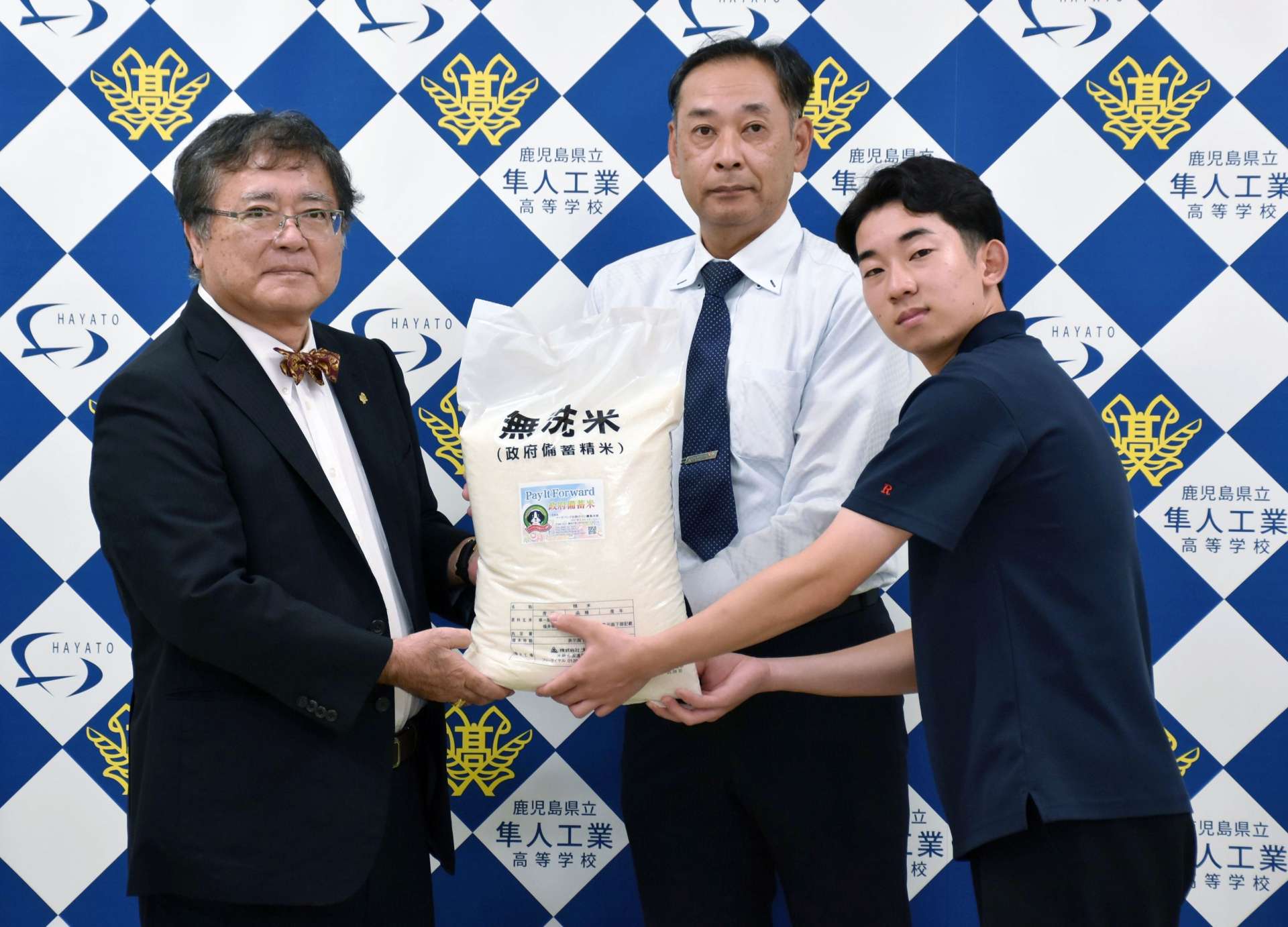 備蓄米を受け取る生徒と保護者＝霧島市隼人町内山田の隼人工業高校