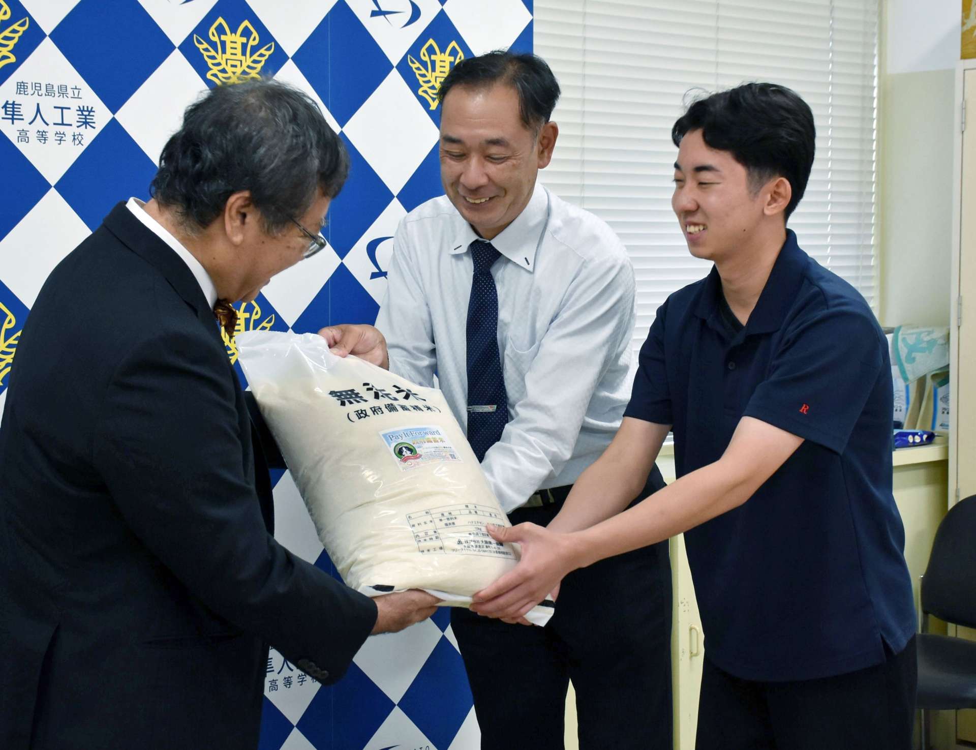備蓄米を受け取る生徒と保護者＝霧島市隼人町内山田の隼人工業高校