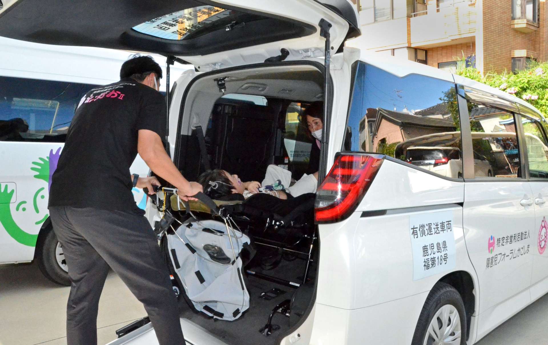専用車に子どもを乗せる職員＝６日、鹿児島市桜ケ丘５丁目の生活支援センターえがおⅡ
