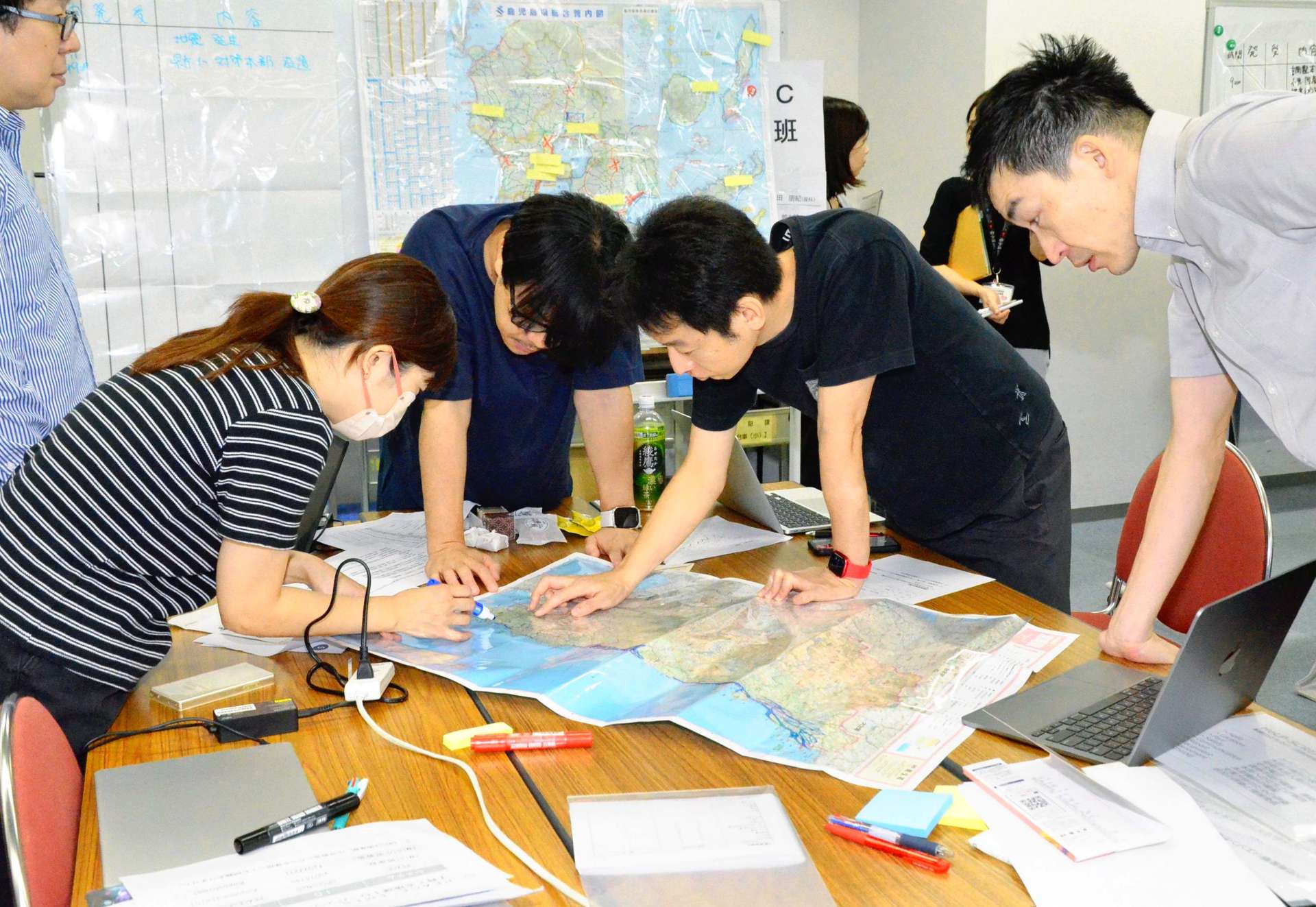 災害場所にチェックを入れ、搬送経路を話し合うリエゾンら＝１１日、鹿児島県庁
