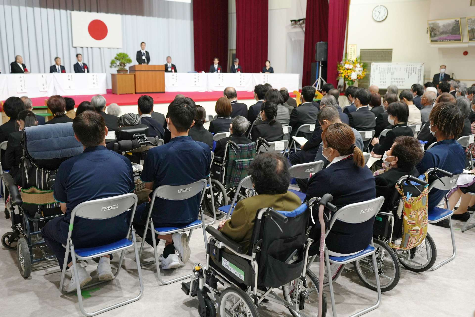 職員に付き添われて式典に参加する入所者ら＝２８日、鹿屋市の星塚敬愛園