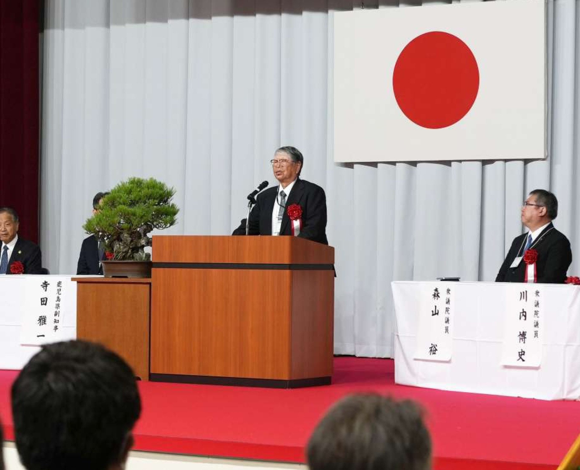 式典であいさつする星塚敬愛園入所者自治会の山口文夫会長＝２８日、鹿屋市の同園