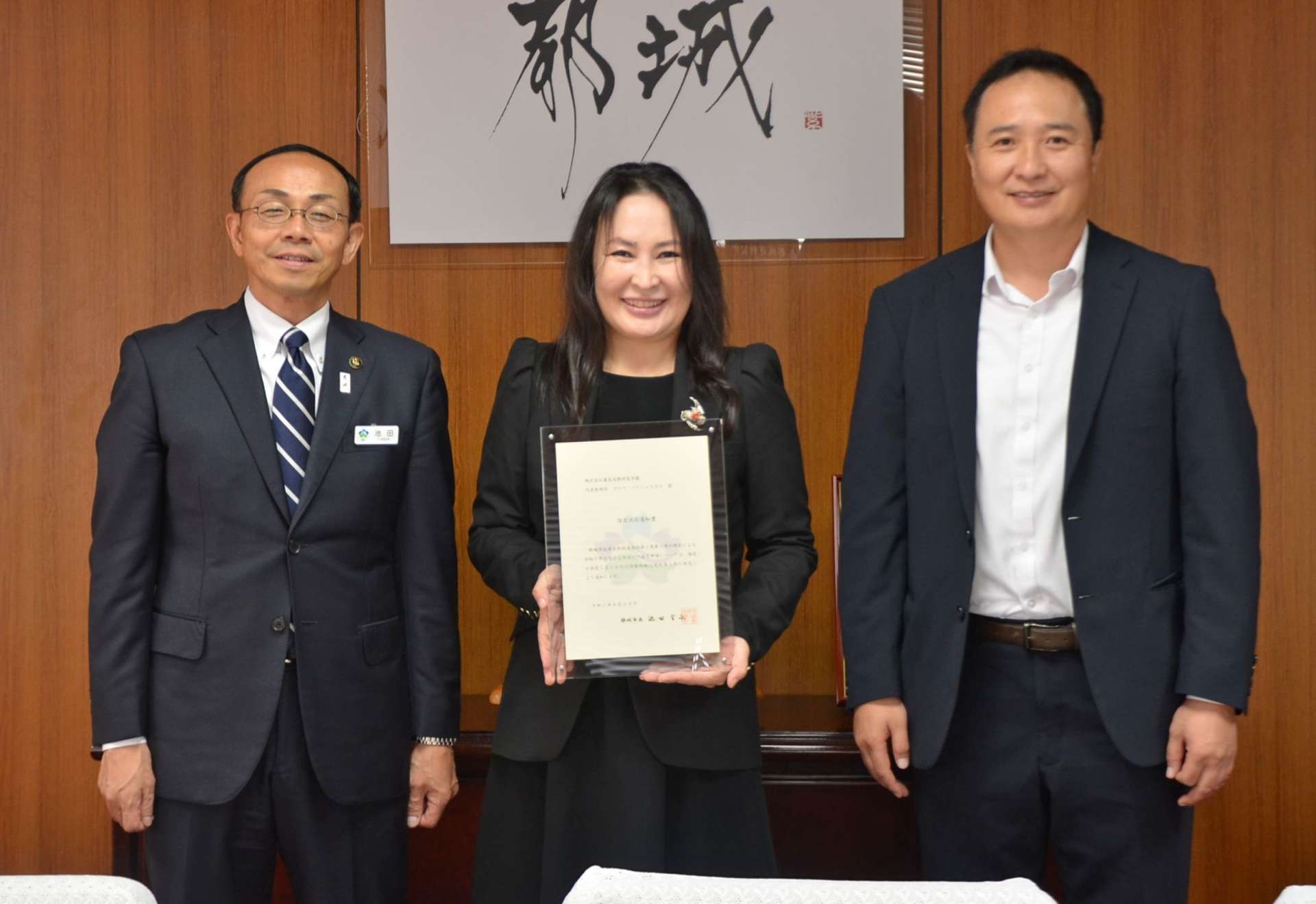 池田宜永市長（左）から指定書を交付されたボリヤ・バドジャルガル社長（中央）＝２８日、都城市役所