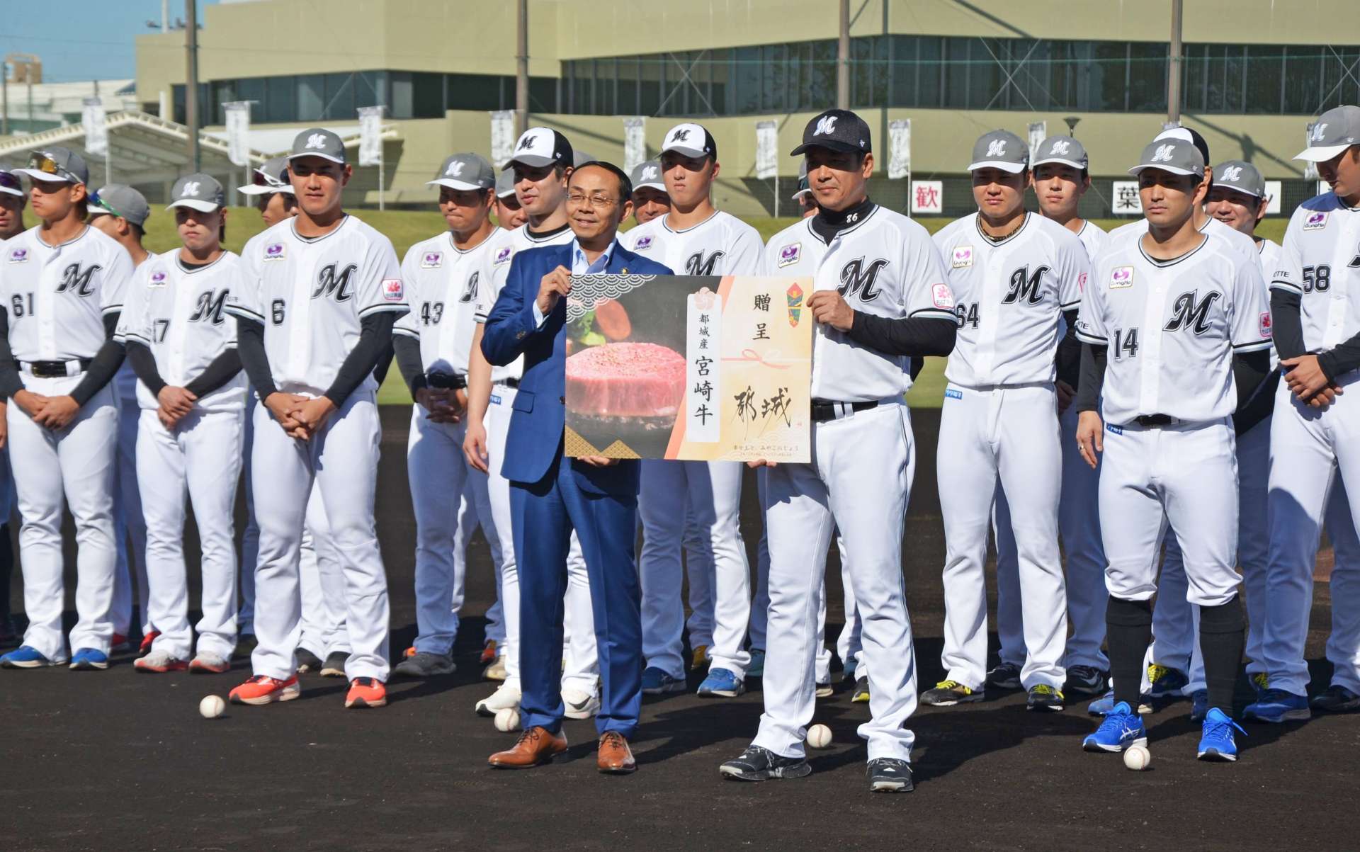 池田宜永市長から都城産宮崎牛の贈呈パネルを受け取るサブロー監督＝２９日、都城市妻ケ丘町の都城運動公園野球場