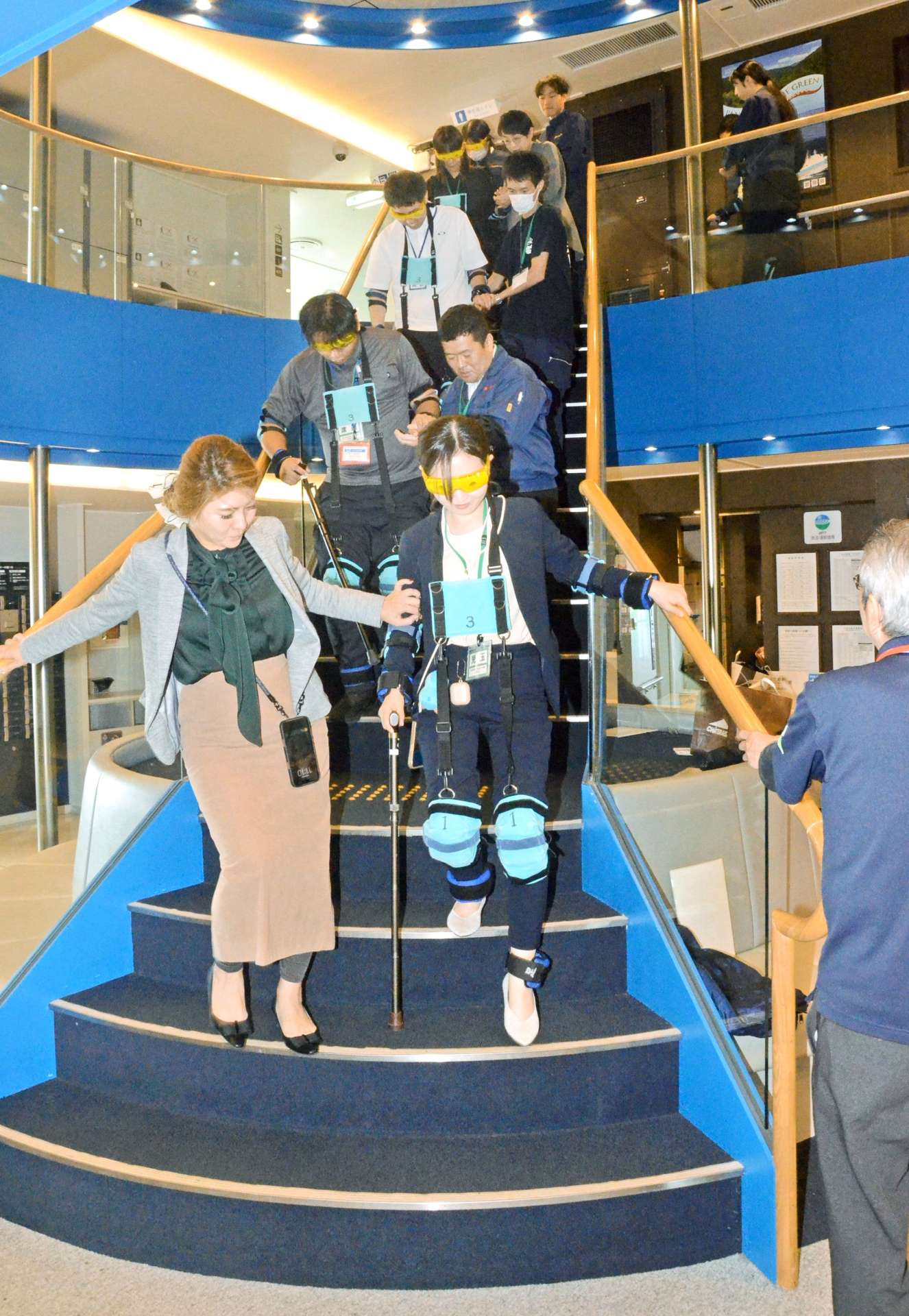 体の動きを制限する器具を着け、高齢者の介助方法を学ぶ参加者＝２９日、鹿児島市