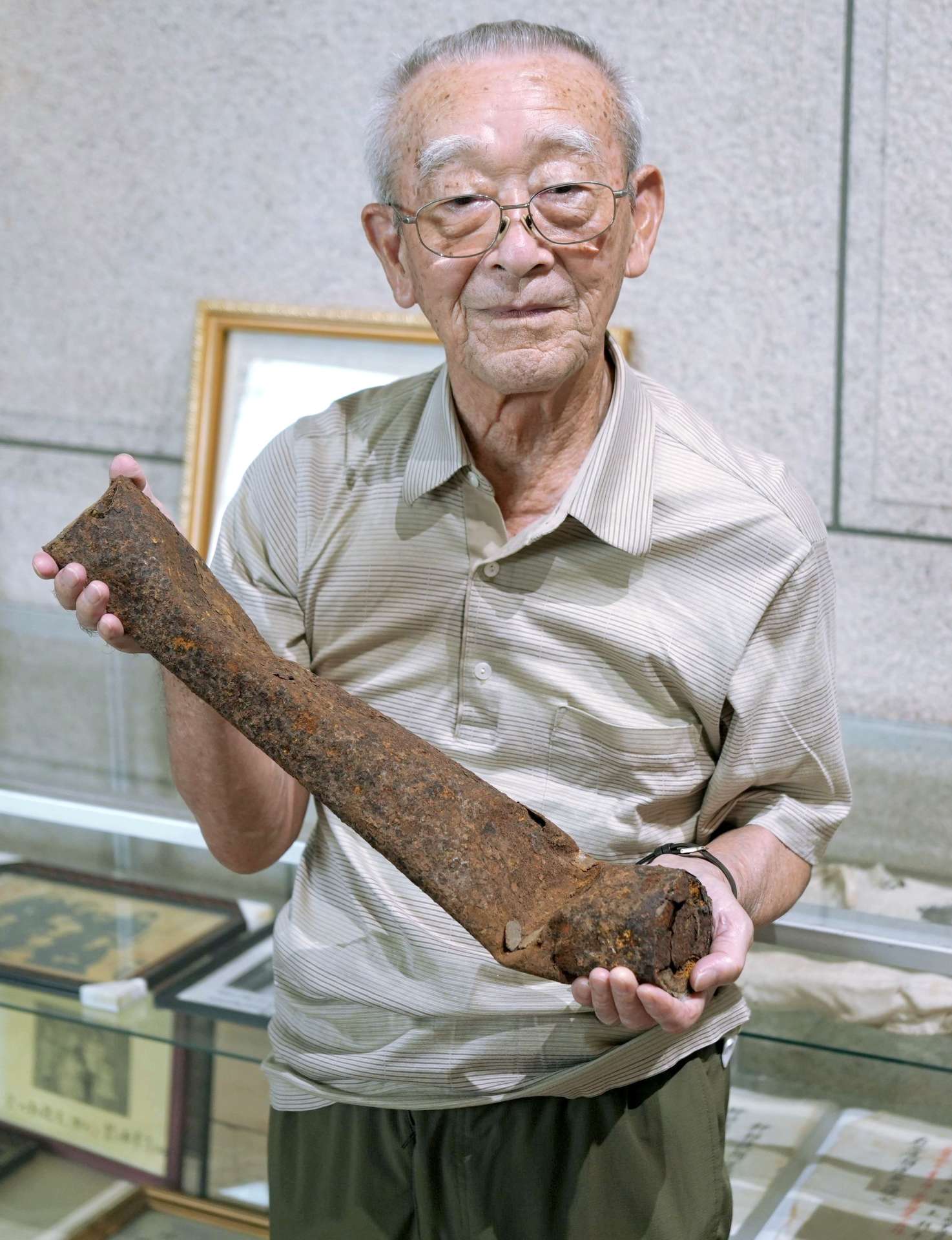 垂水市で発見された焼夷弾を手にする川畑弘見さん＝同市文化会館