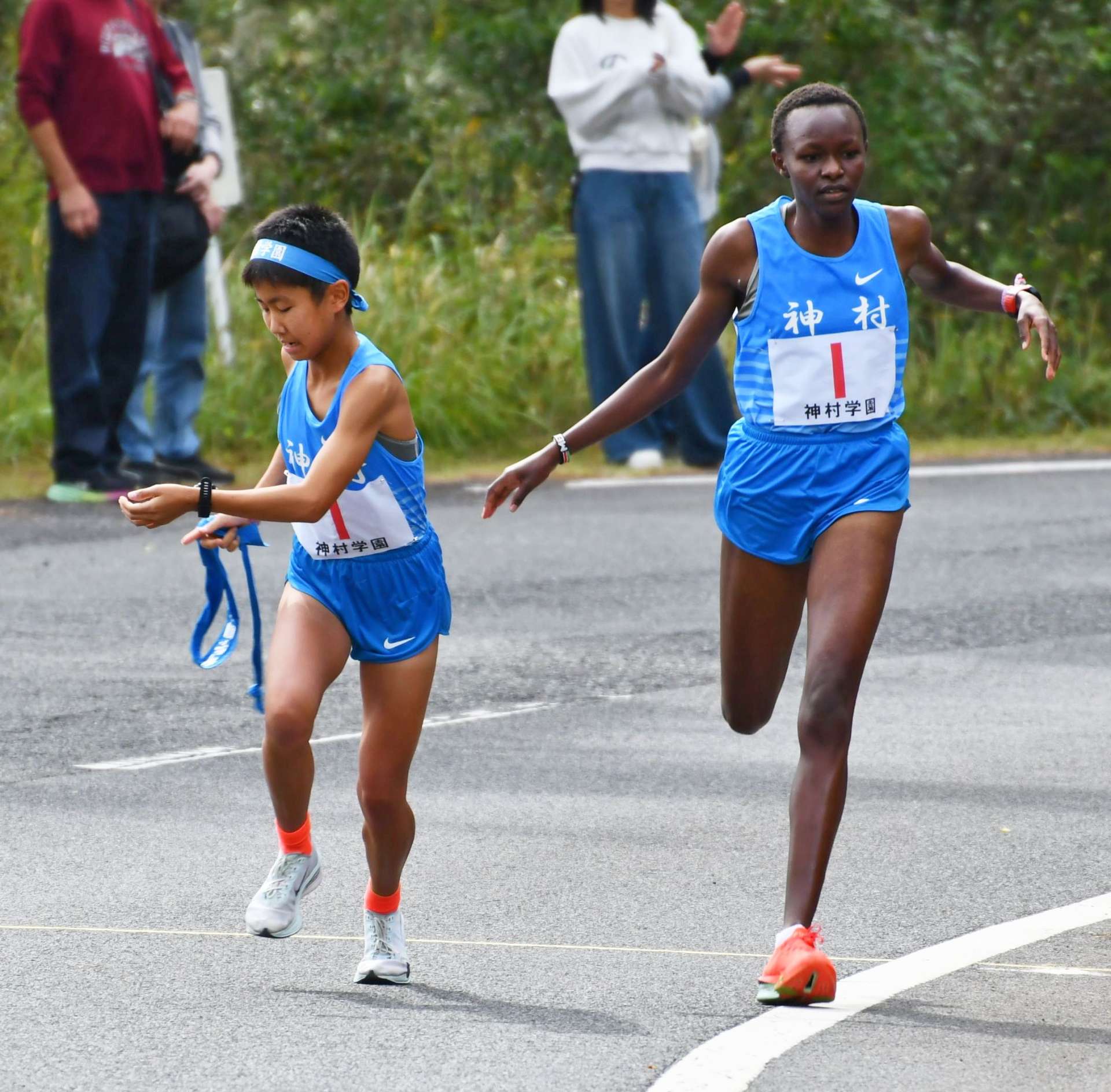 第３中継所、神村・マーシー（右）が武田にたすきリレー＝指宿市