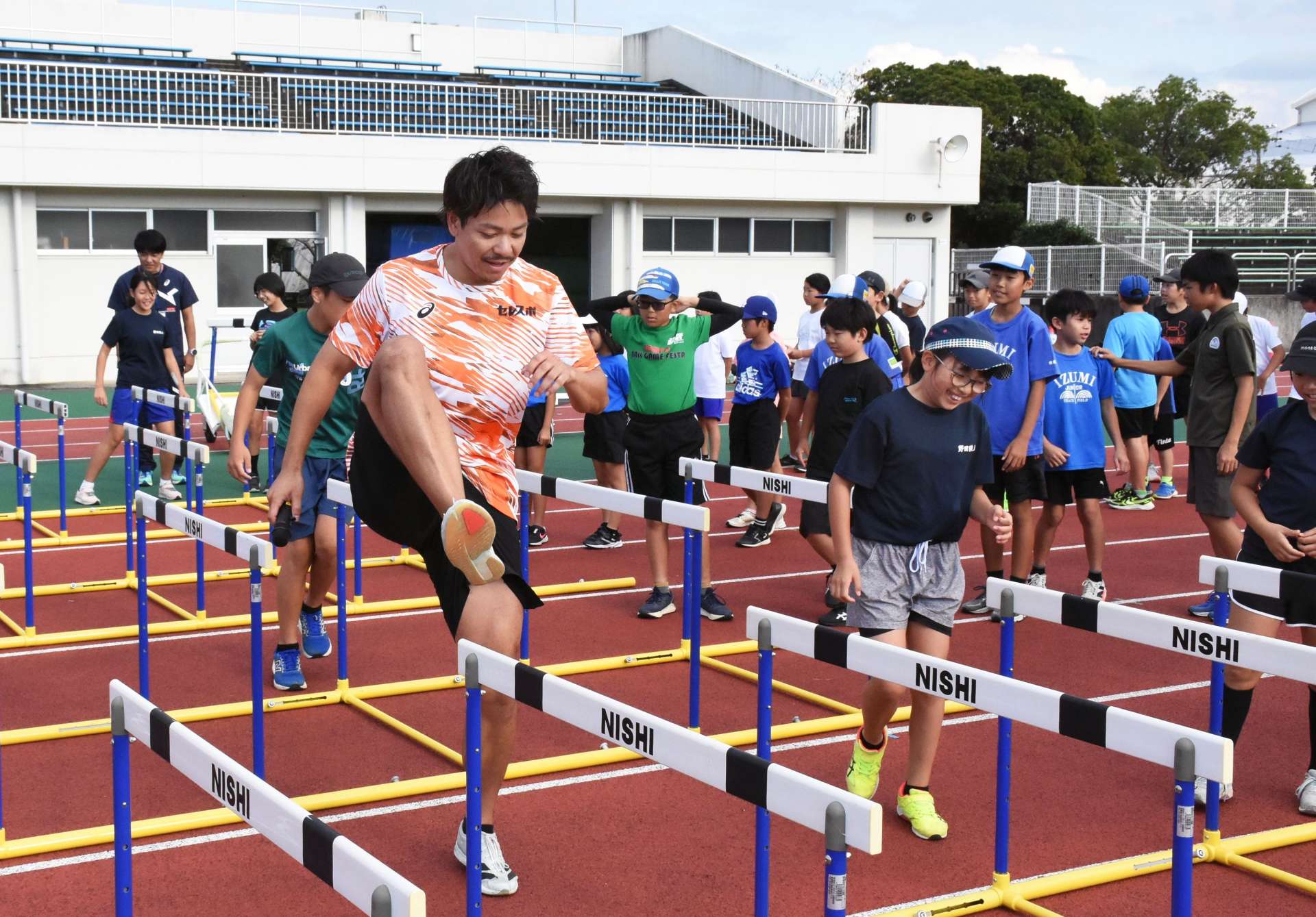 リズムよく太ももを上げるこつを助言する白石黄良々選手＝出水市のマルマエスタジアム出水