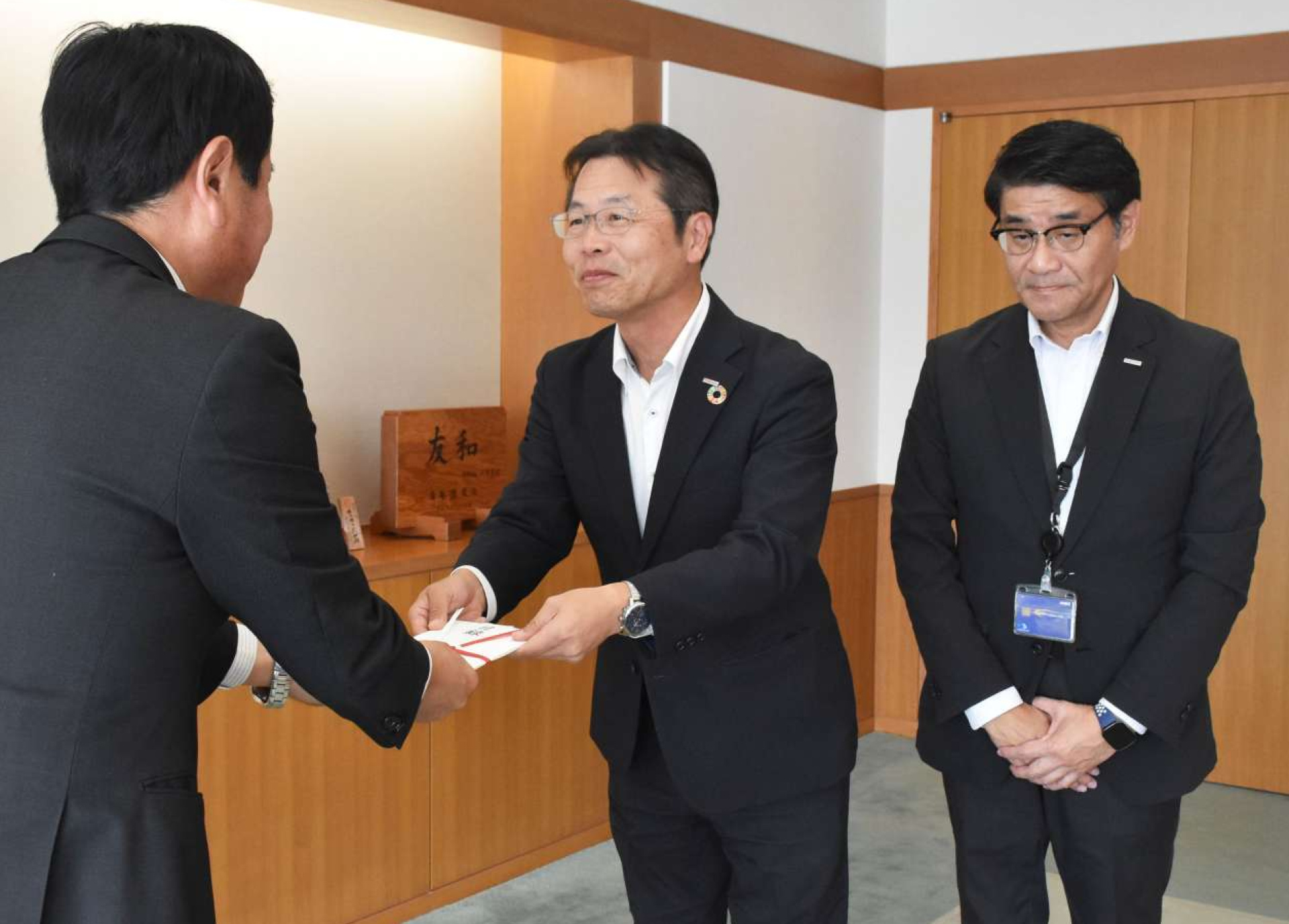 目録を手渡す蓑毛晃次支店長（中央）＝霧島市役所