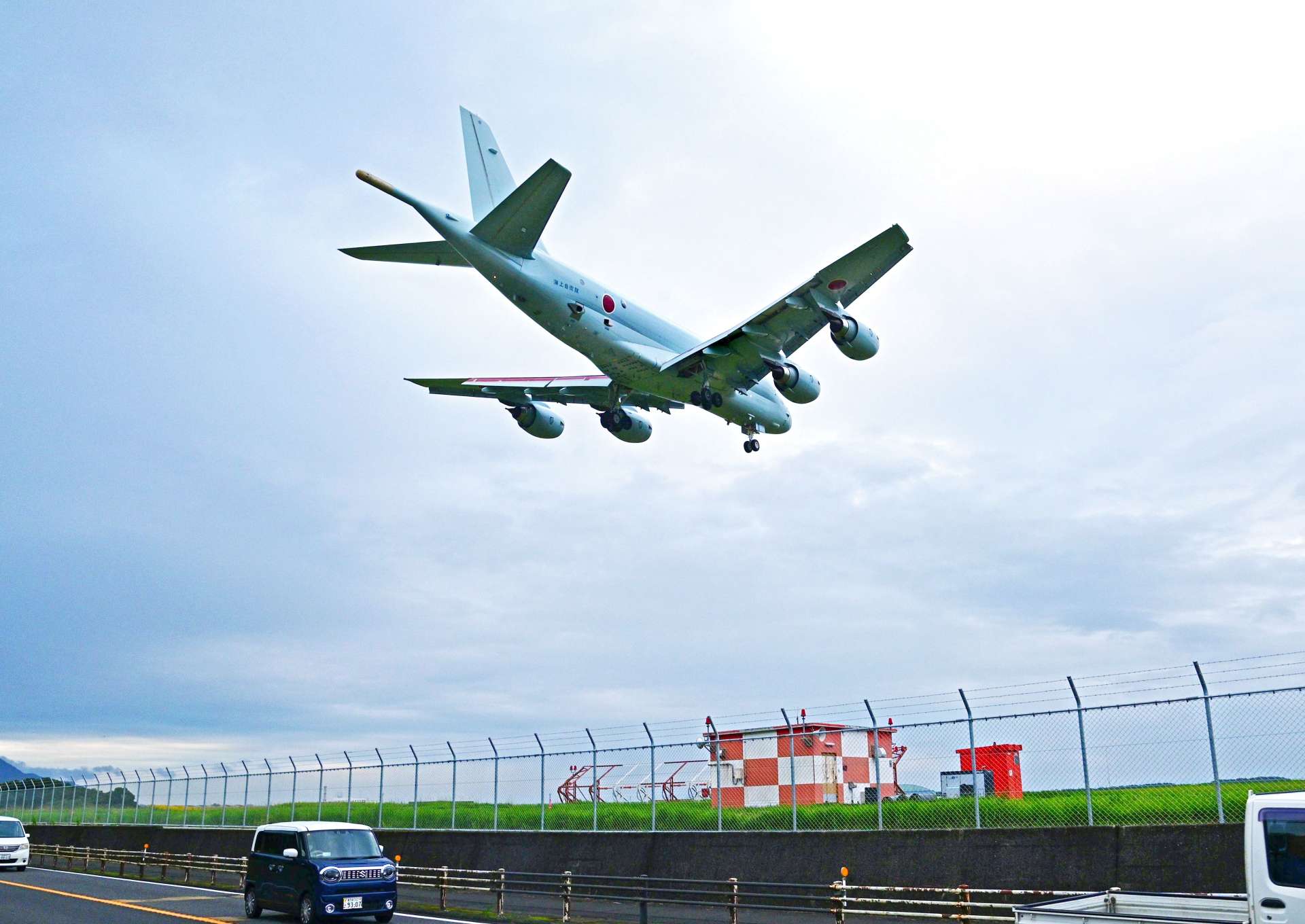 一般道路とフェンスを隔てた海上自衛隊鹿屋航空基地で離着陸訓練を繰り返すＰ１哨戒機＝１０月２４日午後６時、鹿屋市