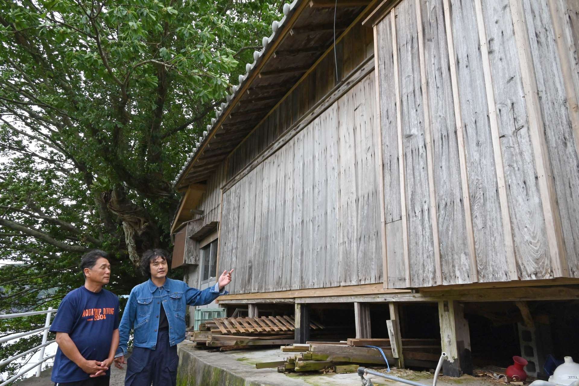 修復が進む「キッシー＆ボンドの家」と（左から）上塘照哉さん、桑原田健史さん＝南さつま市坊津町秋目