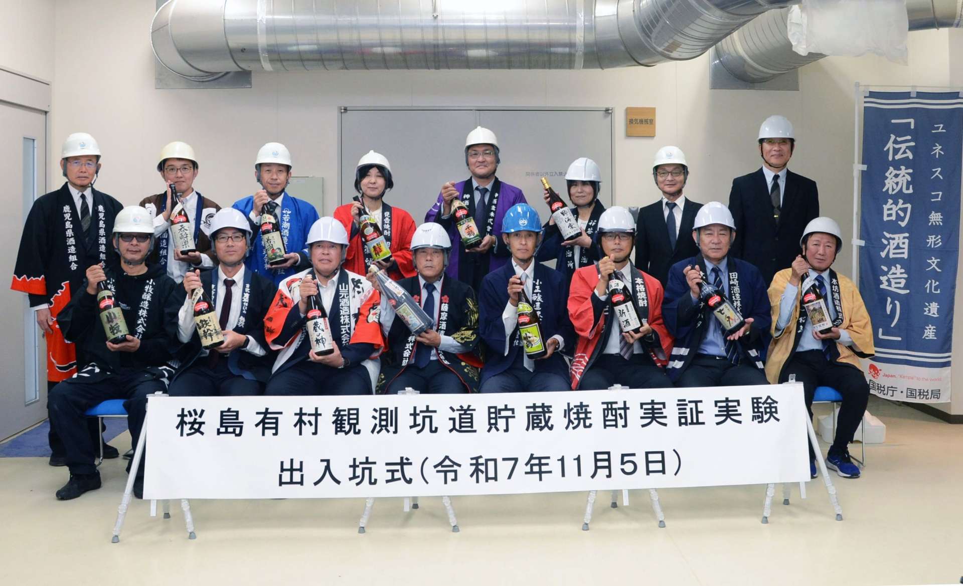 １年間貯蔵した焼酎を手にする蔵元ら＝５日、鹿児島市の桜島有村観測坑道