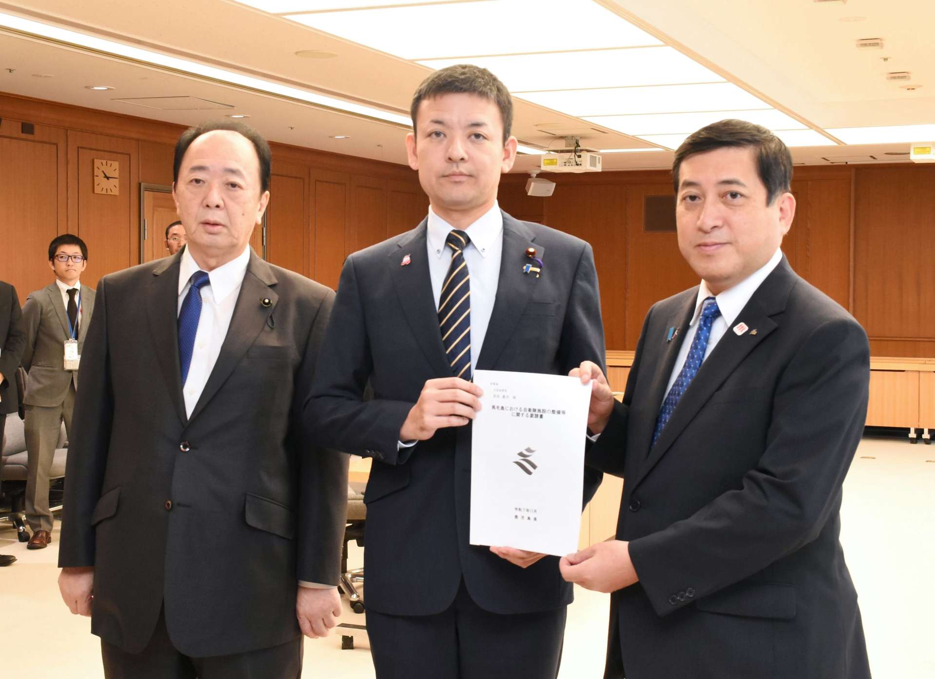 吉田真次防衛大臣政務官（中央）に要請書を手渡す塩田康一知事（右）＝６日、防衛省