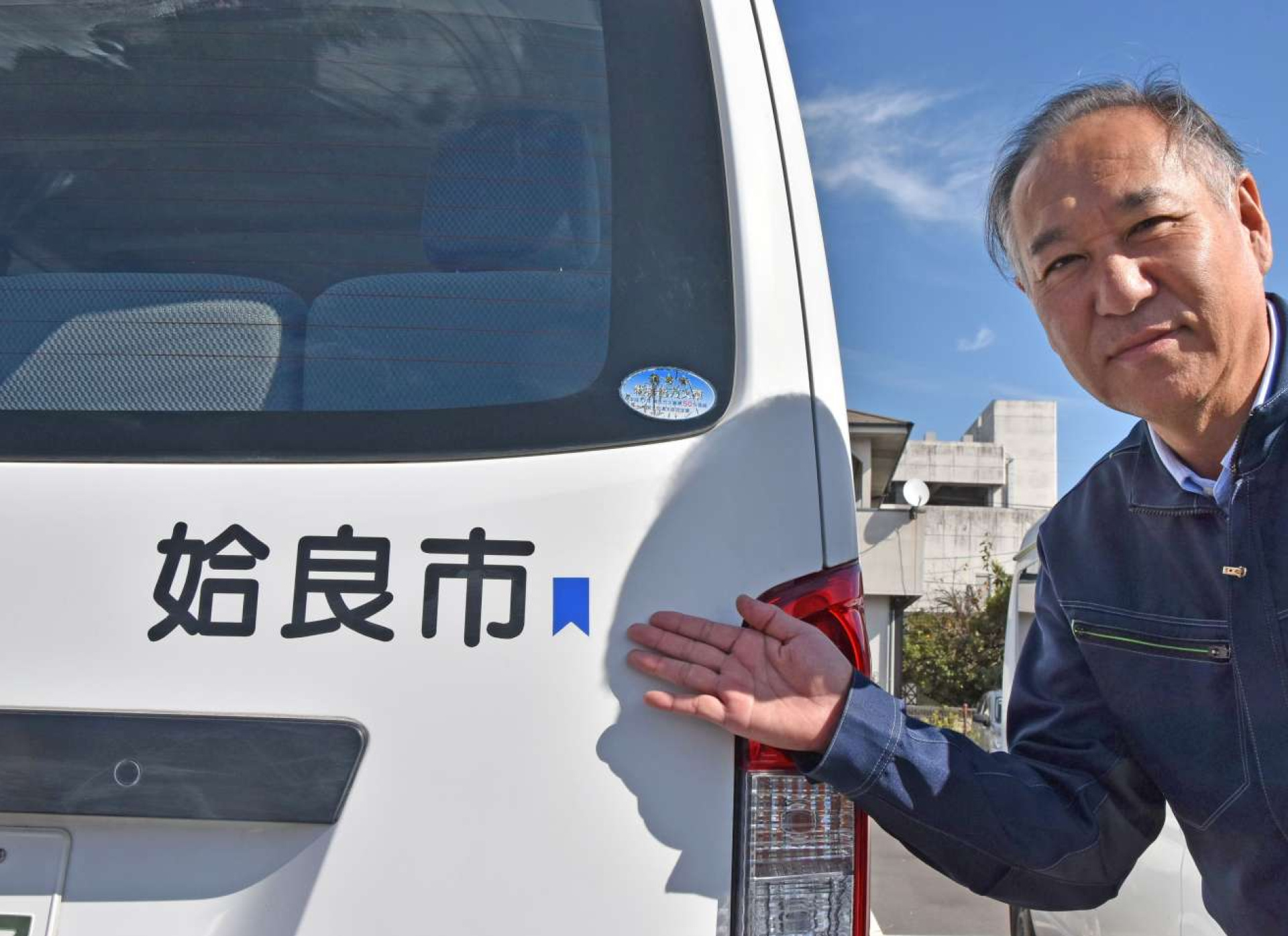 姶良市の公用車に貼られたブルーリボンステッカーと作製した森山博行さん＝良市役所