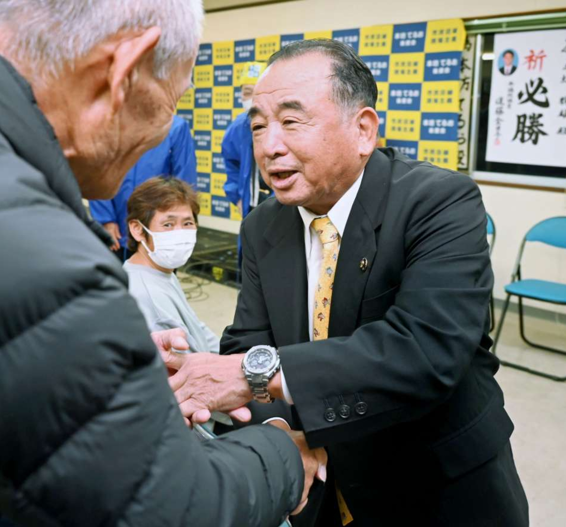 無投票当選が決まり支持者と握手する本坊輝雄氏＝９日、南さつま市加世田麓町