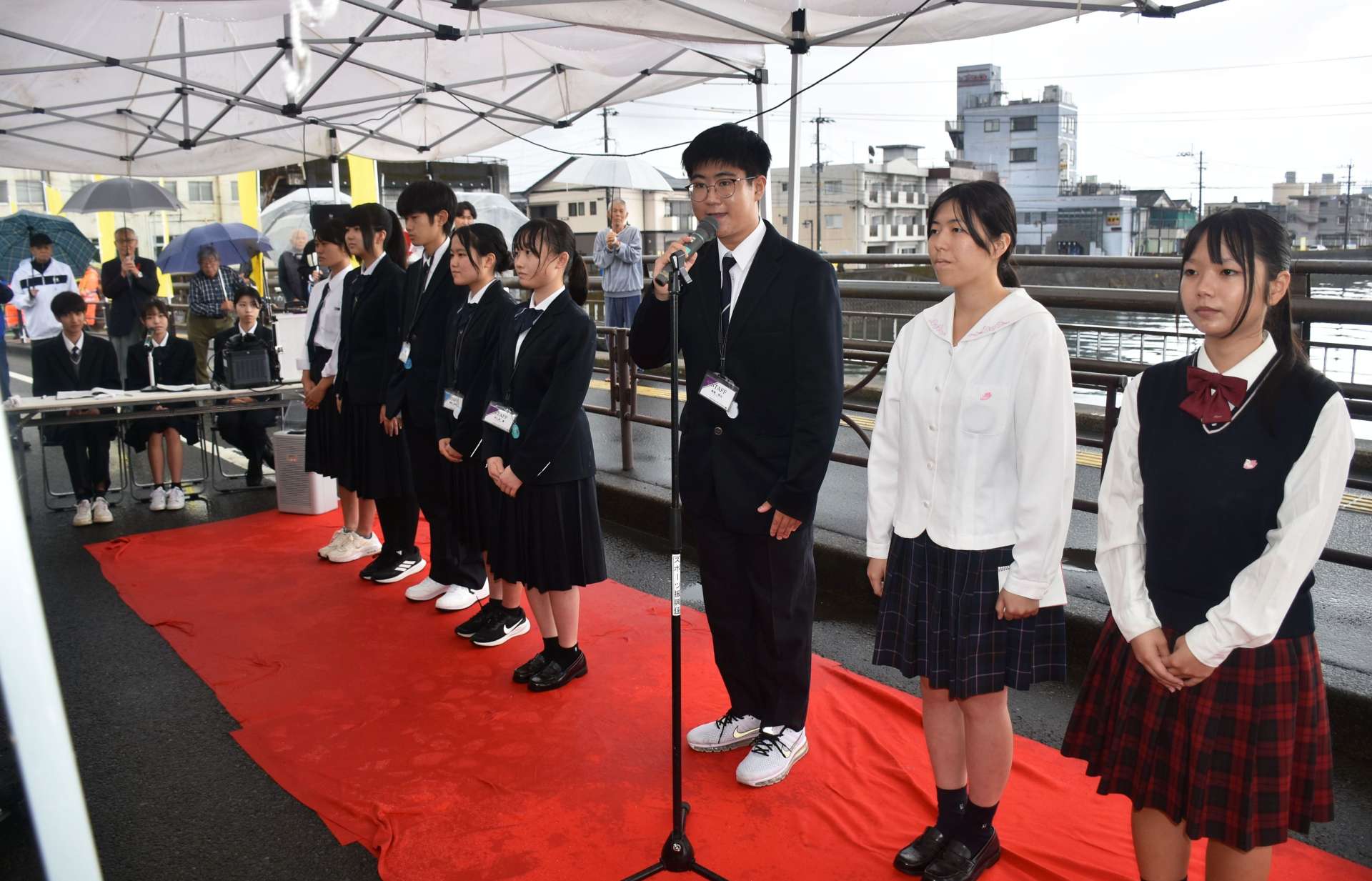 網掛橋で地域の復興を願うメッセージを披露する地元高校生ら＝９日、姶良市加治木