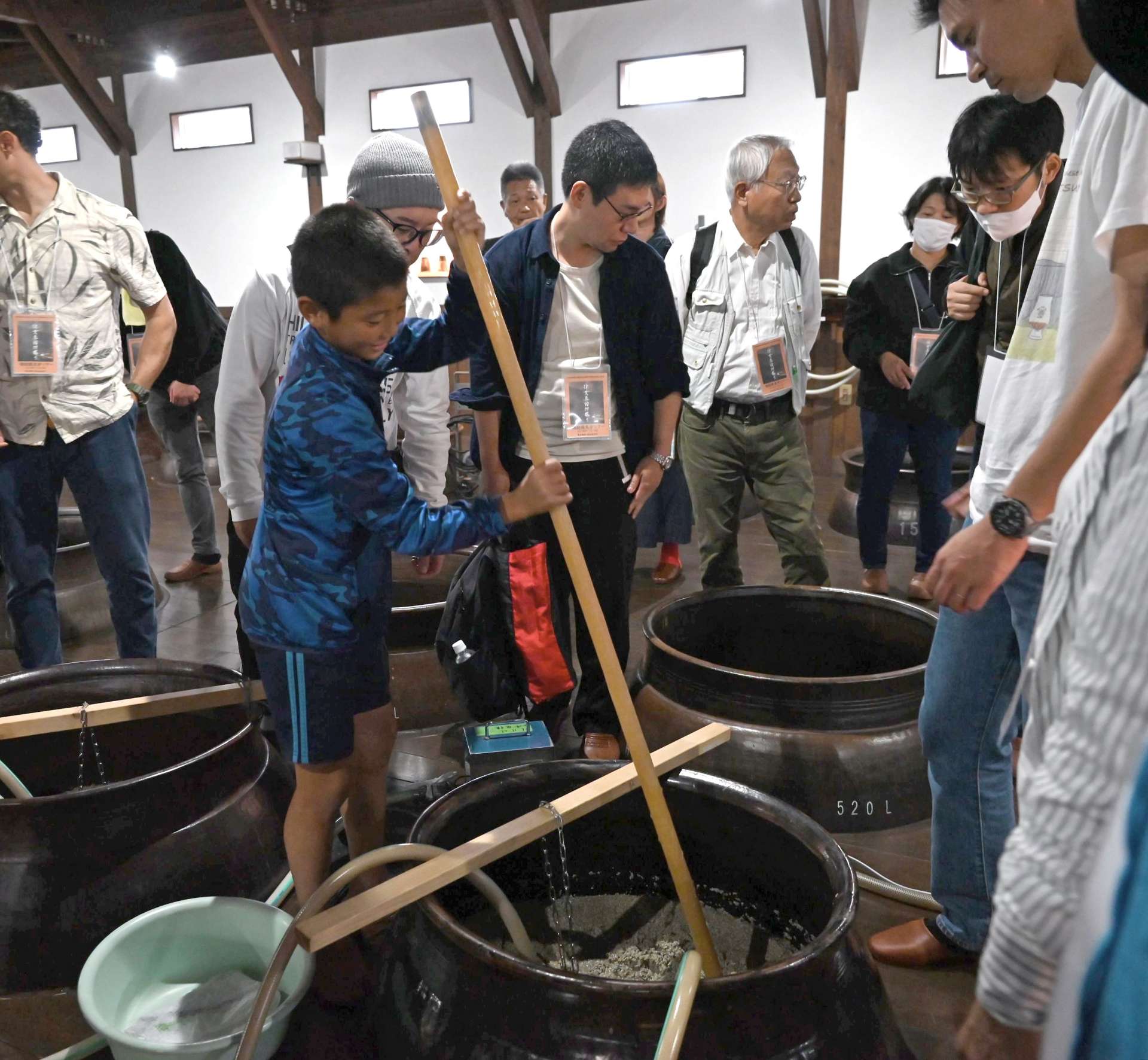 かめに入ったもろみを混ぜる参加者＝南さつま市加世田津貫