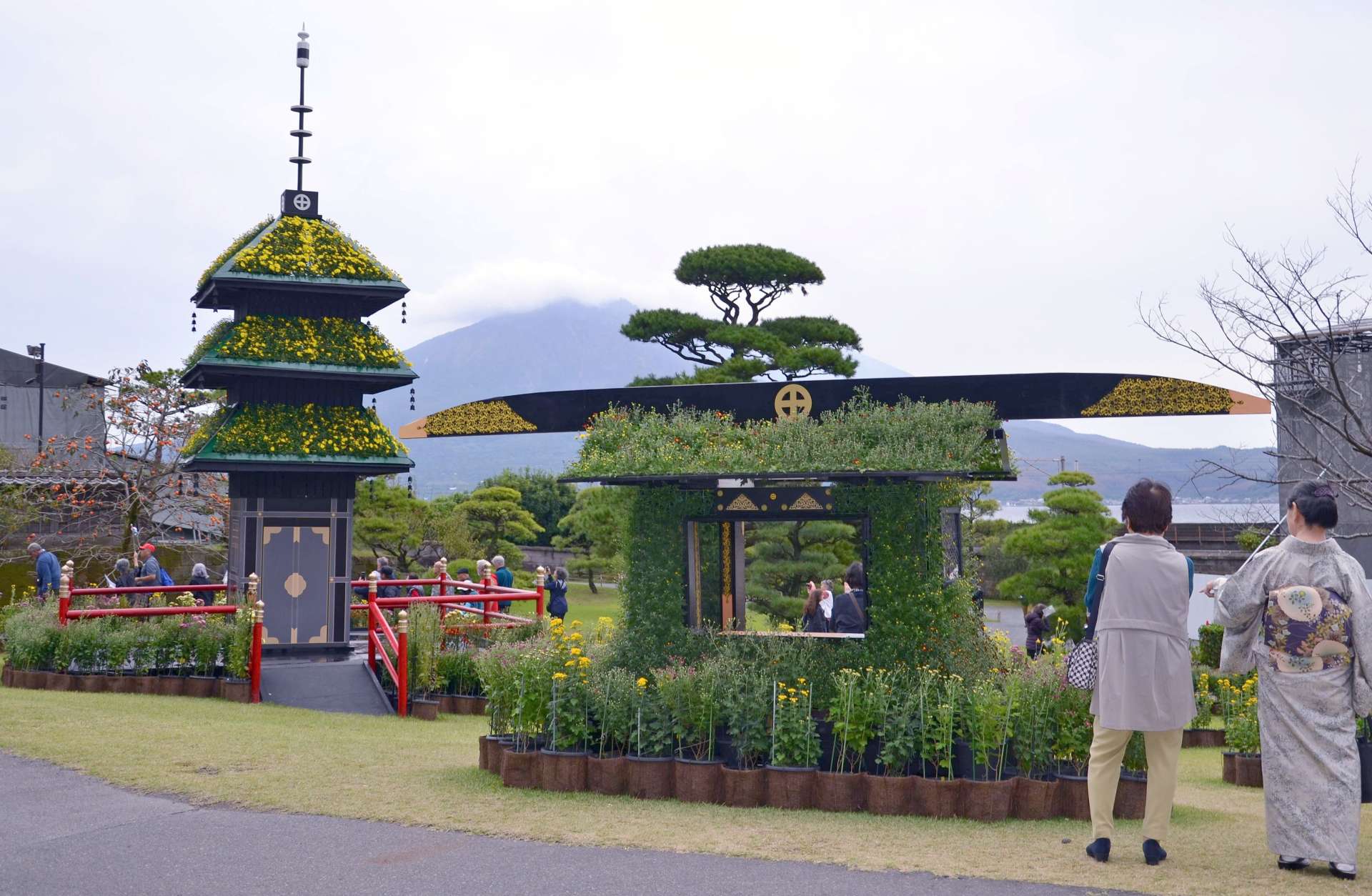 桜島を望む庭園に並んだ三重塔や駕籠の作品＝１２日、鹿児島市の仙巌園