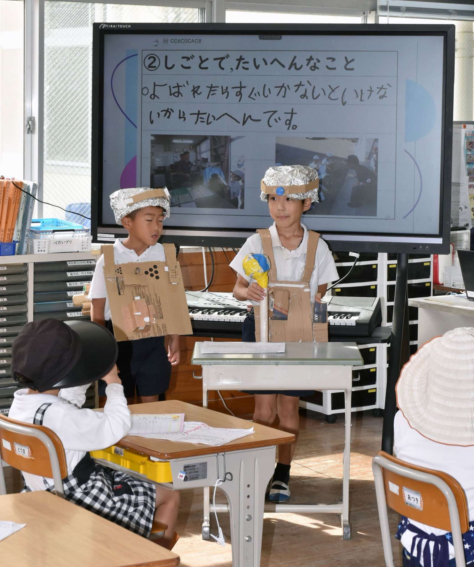 自作の消防服を着て、消防署の仕事について学んだことを発表する児童ら＝伊佐市の菱刈小学校