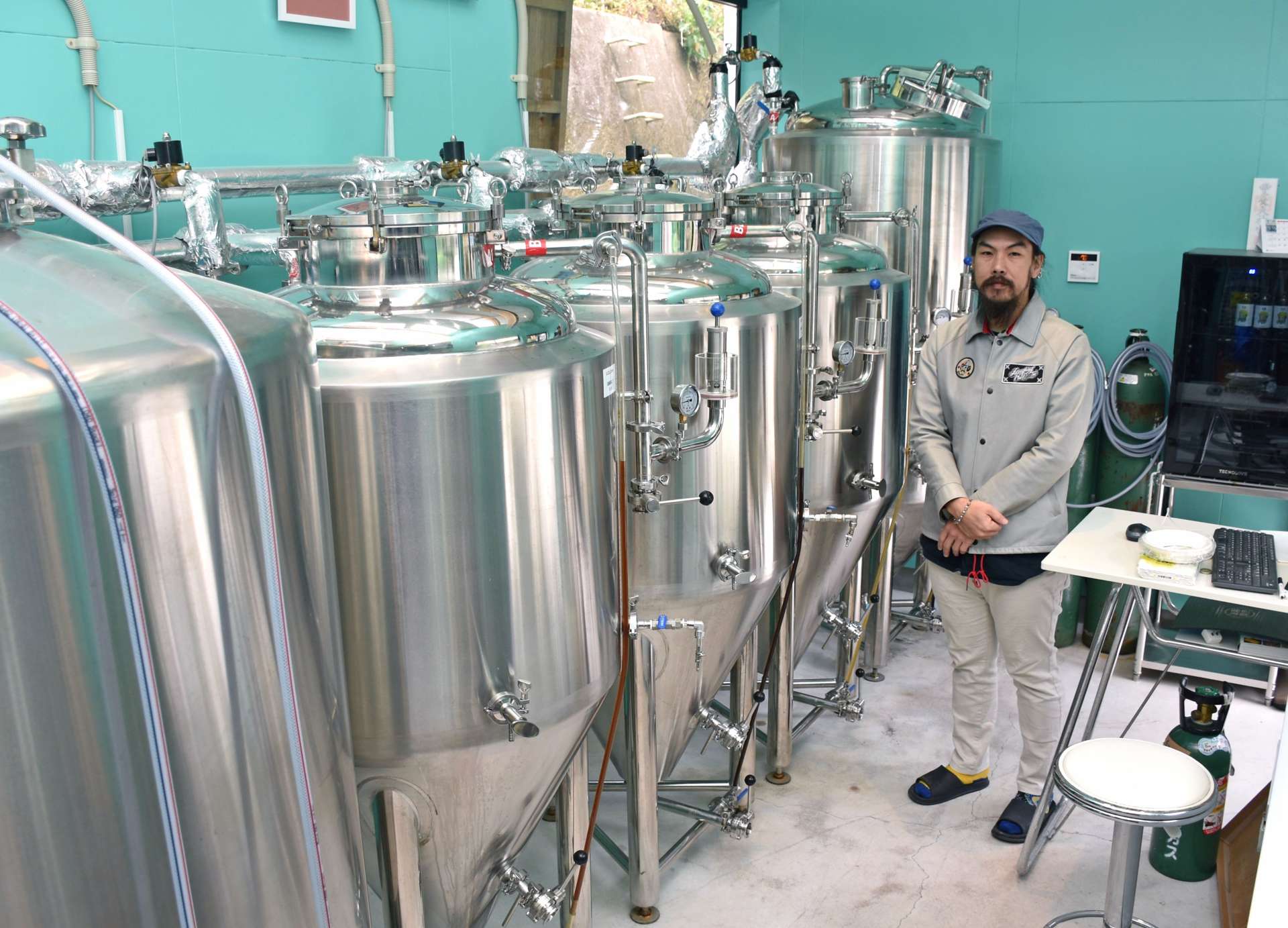 クラフトビールを醸造する機械の前に立つ松田裕之さん＝薩摩川内市下甑町手打