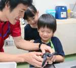 ウミガメと触れ合う梅本一輝ちゃん（中央）と姉の真友美さん＝鹿児島市本港新町のかごしま水族館