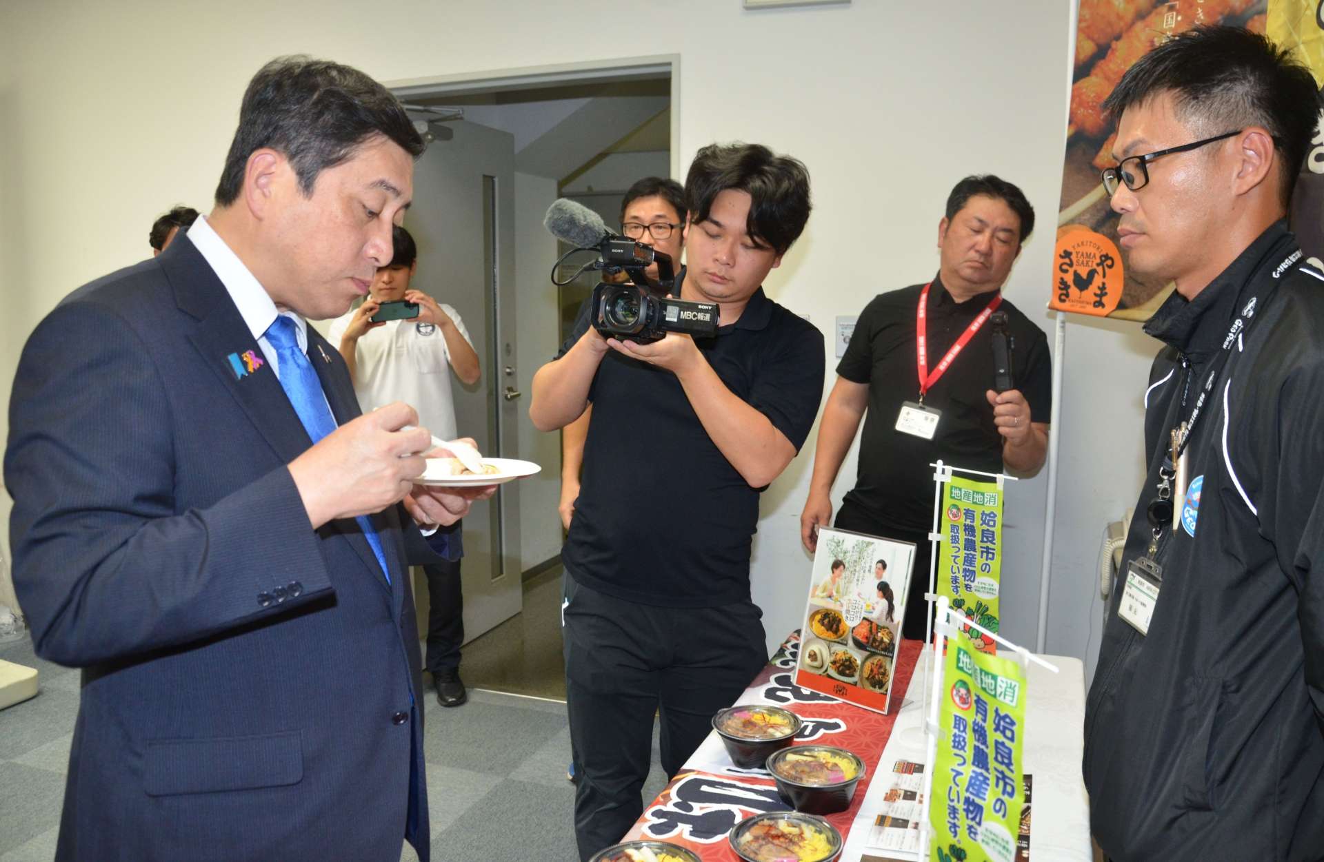 「薩摩おいどんリーグ」で提供される「炊き込み焼き鳥丼（姶良市）」を試食する鹿児島県の塩田康一知事（左）