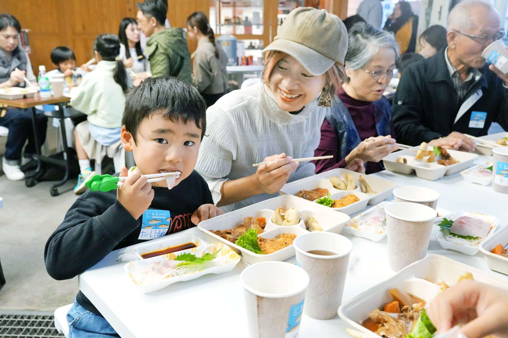 カンパチを食べながら大隅半島の海や魚について学ぶイベント参加者＝鹿屋市新川町