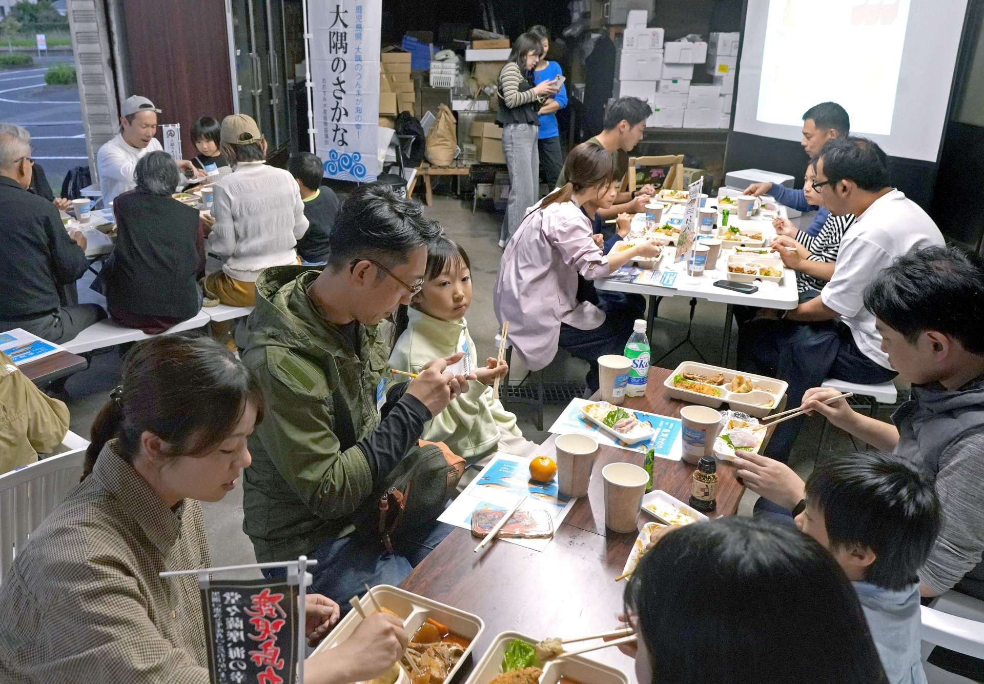 カンパチを食べながら大隅半島の海や魚について学ぶイベント参加者＝鹿屋市新川町