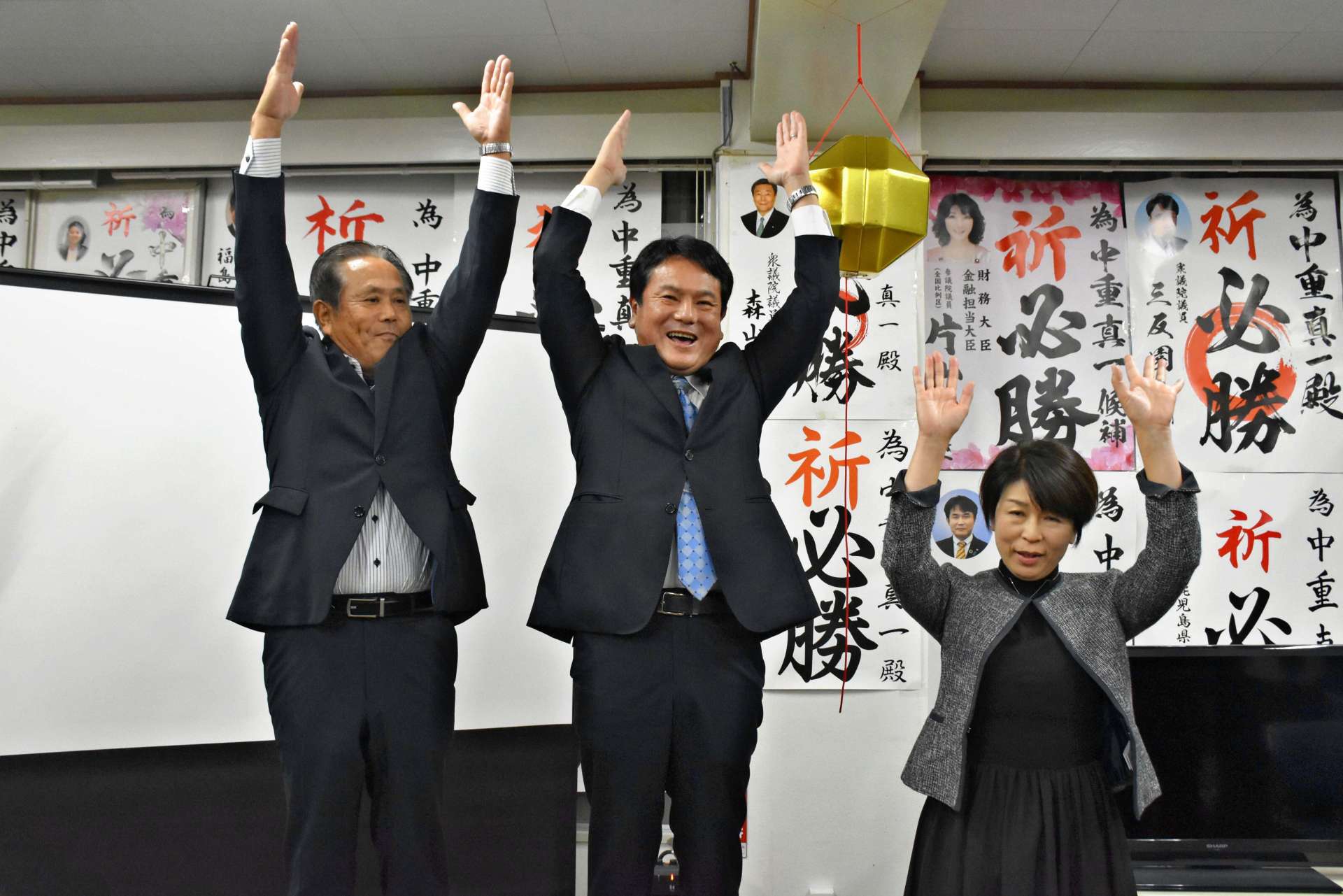 ３期目の当選を果たし、万歳する中重真一さん（中央）＝１６日午後１０時４０分ごろ、霧島市国分中央３丁目