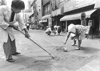 昭和60年7月、鹿児島市千日町。記録的な降灰に見舞われた街は朝から市民総出で除去作業。市から配布された降灰袋は使い果たすほどだった。