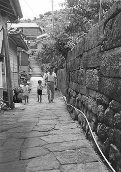 昭和46年、旧笠沙町片浦の石だたみ。「笠沙路は石だたみと石垣の美しい町だ。平地の少ない山肌を切り開き、石垣を積んで段々畑みたいな集落を形造っている。石は椎木部落の産。赤味を帯び、しっとりとした落ち着きをみせている」と紹介している。