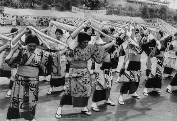昭和４９年４月１０日、黒之瀬戸大橋開通の祝賀会で披露された婦人会員らの手踊り。紙面は「東、長島両町（現長島町）で開通の祝賀祭りがあり、長島町は全町民が会場の長島中学校までパレード。婦人会員の踊りなどがあり、町民は焼酎をくみ交わしながら“離島脱出”を喜び合った」と報じている。