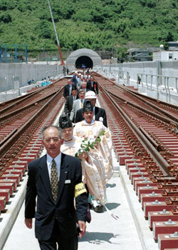 平成１４年７月、鹿児島市から大型トレーラーで伊集院町（現日置市）の日本鉄道建設公団神殿基地に運ばれる新幹線のレール。当時の紙面は「北九州市の製鉄所で作られ、船で鹿児島港谷山二区に運ばれたあと陸送。全長２５メートル、重さ１．５トンもあり、１台のトレーラーに積めるのは１３本が限度」と伝えている。