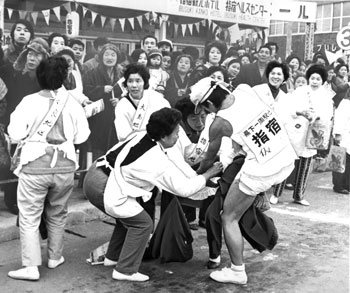 昭和４８年、第２０回県下一周駅伝大会。指宿中継所で婦人会も選手の介抱に大わらわ。紙面では「初日の５区の中継点になった指宿駅前。婦人会員が全力を出し尽くした選手を抱きかかえるようにして休憩所へ。それぞれ担当チームがあったが選手を見るとそれを忘れて全員が駆け寄って介抱する。汗を拭いたり、お茶を出したり、まるでわが子の様な世話ぶり。感激した選手らはいつまでも別れを惜しんでいた」と報じている。